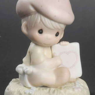 Porcelain figurine of baby in hat holding a Valentine Card (heart)