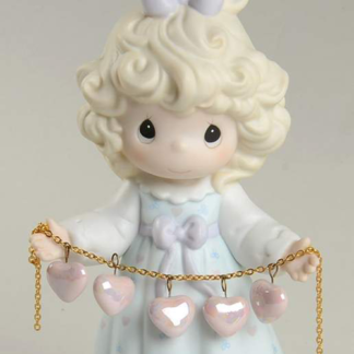 Precious Moments figurine features a girl holding a pearlized string of hearts