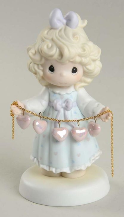 Precious Moments figurine features a girl holding a pearlized string of hearts
