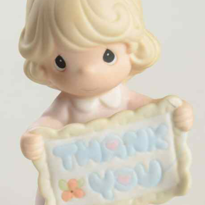 porcelain figurine features a young girl holding a thank you banner.
