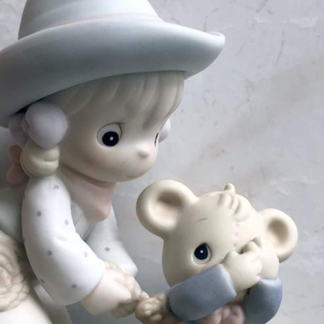 Porcelain figurine of a cowgirl lassoing a teddy bear.