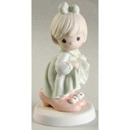 Porcelain figurine of little girl playing dress up with woman's shoes