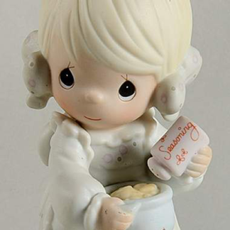 Precious Moments figurine depicts a girl sprinkling seasoning in a mixing bowl.