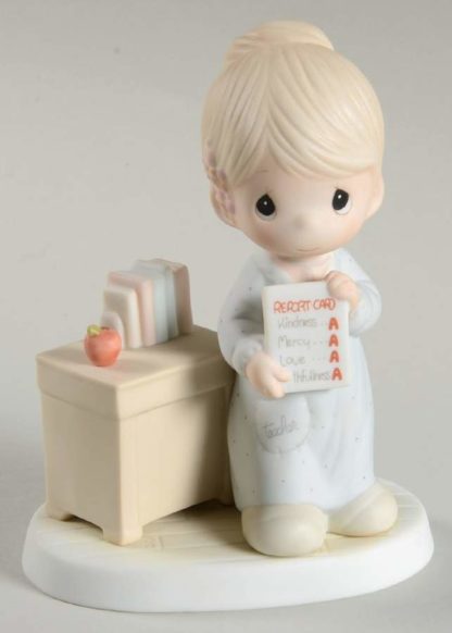 Precious Moments figurine of a teacher at her desk holding a report card