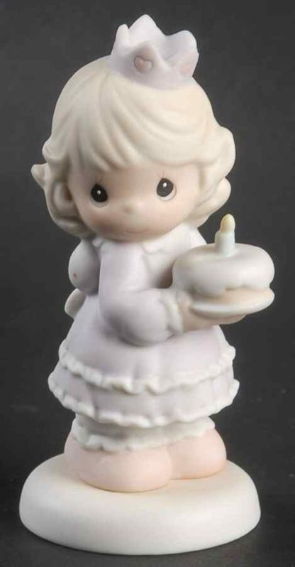 This porcelain figurine depicts a girl wearing a crown and holding a cake.