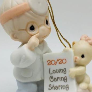 Porcelain ornament depicts A Boy Optometrist With A Cat Holding A Sign. 