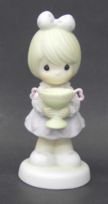 Precious Moments figurine depicts a girl holding loving cup (trophy).