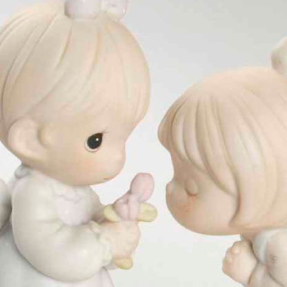Precious Moments figurine depicts two girls smelling a flower.