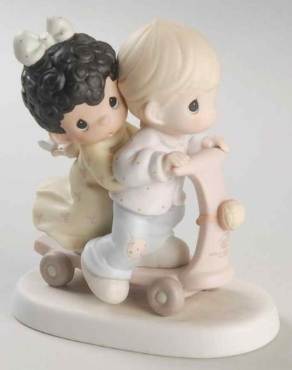 Precious Moments figurine of Love is Color blind featuring a boy and girl riding together on a scooter.