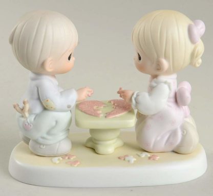 Precious Moments figurine depicts a boy and girl putting a puzzle together at a table.