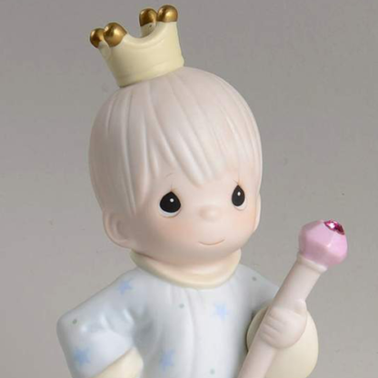 porcelain figurine depicts a boy with a crown, robe and jeweled staff.
