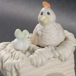 porcelain figurine depicting chicken with egg on hay-filled cart.
