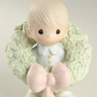 porcelain figurine depicts a boy with a Christmas Wreath around him.
