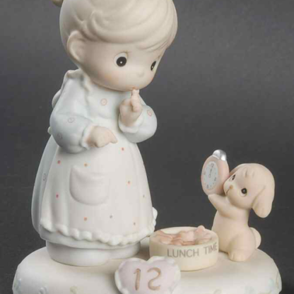 Porcelain figurine from the Growing In Grace series, this piece depicts a girl with a puppy holding a clock